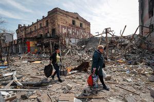 Residentes llevan sus pertenencias cerca de edificios destruidos en el curso del conflicto entre Ucrania y Rusia, en la ciudad portuaria sureña de Mariupol, Ucrania, 10 de abril de 2022. Foto REUTERS/Alexander Ermochenko.