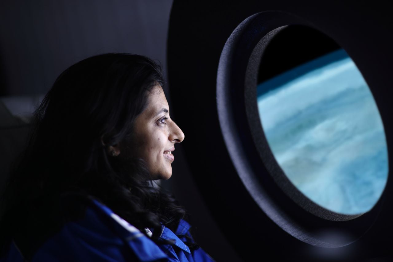 Un viajero espacial comercial mirando la Tierra a través de la ventana de una nave espacial.