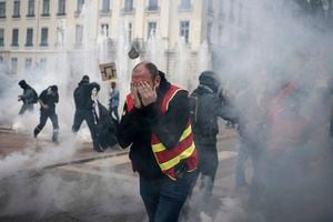 Los manifestantes corren en medio de los gases lacrimógenos durante una manifestación en Lyon, centro de Francia, el jueves 23 de marzo de 2023. (AP Photo/Laurent Cipriani)