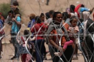 Los migrantes se paran cerca del muro fronterizo después de haber cruzado la frontera entre Estados Unidos y México para entregarse a los agentes de la Patrulla Fronteriza de los Estados Unidos, visto desde Ciudad Juárez, México, el 11 de mayo de 2023. 