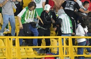 Supporters of Atletico Nacional violently kick a fan of Independiente Santa Fe, who is on the ground, during a clash inside the Nemesio Camacho El Campin stadium on its day of reopening to the public after being closed by the Covid-19 pandemic in Bogota on August 3, 2021. (Photo by STR / AFP)