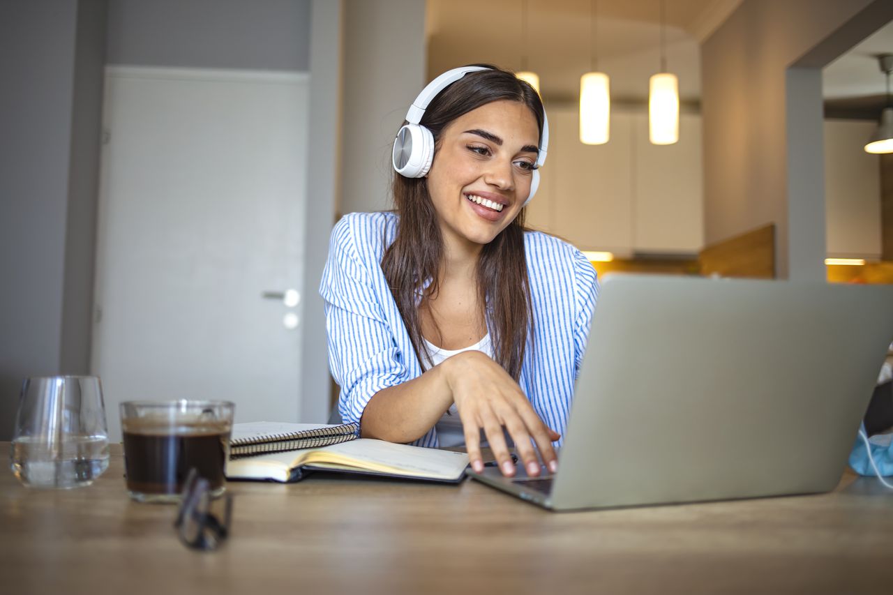 Mujer estudiante toma clases virtuales con audífonos, clases por internet