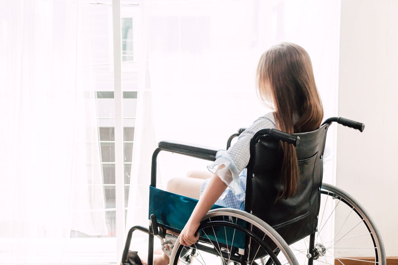 Niña sentada en silla de ruedas en el hospital