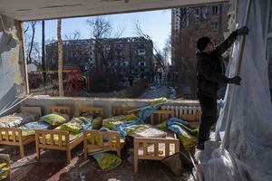 Un hombre quita una cortina destruida dentro de una escuela dañada entre otros edificios residenciales en Kiev, Ucrania, el viernes 18 de marzo de 2022. Las fuerzas rusas intensificaron su asalto a las ciudades ucranianas el viernes, con nuevos ataques con misiles y bombardeos en los bordes de la capital, Kiev, y la ciudad occidental de Lviv, mientras los líderes mundiales presionaban para que se investigaran los repetidos ataques del Kremlin contra objetivos civiles, incluidas escuelas, hospitales y zonas residenciales. Foto AP/Rodrigo Abd