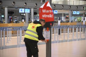 Un representante sindical pega un cartel que dice "¡Aviso de huelga!" y un volante en el tablero de anuncios en la Terminal 2 vacía del Aeropuerto de Hamburgo, en Hamburgo, Alemania, el domingo 12 de marzo de 2023. (Jonas Walzberg/dpa via AP)