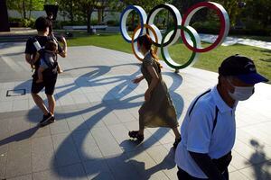 Transeúntes pasan frente a los anillos olímpicos en Tokio el 9 de junio del 2021. Hay una fuerte oposición a la realización de los Juegos Olímpicos, pero demasiados intereses en juego, que hacen que los organizadores insistan en realizar la justa en medio de una pandemia. (AP Photo/Eugene Hoshiko, File)