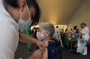A woman is given a dose of the Pfizer-BioNTech vaccine against COVID-19 at the vaccination center set up at the Campo Marte, Mexico City on April 12, 2021. (Photo by ALFREDO ESTRELLA / AFP)