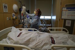 La enfermera Nikki Hollinger limpia una habitación frente al cuerpo de una víctima de covid-19 en un centro médico de Los Ángeles. (AP Foto/Jae C. Hong)