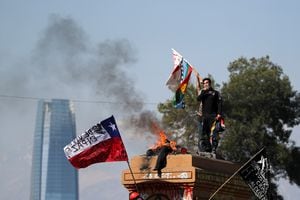 Un manifestante ondea banderas mientras otros silban durante una protesta contra el gobierno de Chile, el 18 de octubre de 2021. Foto REUTERS / Ivan Alvarado