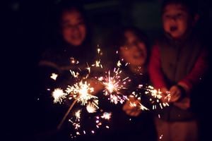 A child is playing sparklers with his family at night