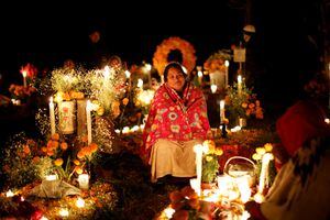 Una mujer se sienta junto a una tumba durante el día de los muertos en un cementerio de la comunidad indígena purépecha de Cucuchuchu, estado de Michoacán, México, 2 de noviembre de 2022. 