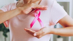 Una mujer asiática muestra una cinta rosa como señal del mes de octubre para concientizar sobre el cáncer de mama