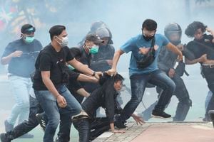 F09 En medio de nubes de gas lacrimógeno, agentes de policía vestidos de civil detienen a manifestantes durante una manifestación en Yakarta. Foto: AP / Tatan Syuflana
