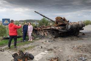 La gente posa para una foto frente a los escombros de la maquinaria militar rusa destruida durante la invasión rusa de Ucrania, en el pueblo de Rusaniv, región de Kiev, Ucrania, 25 de abril de 2022. Foto REUTERS/Vladyslav Musiienko