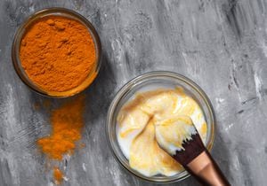 Natural face mask with turmeric powder and yogurt. Natural cosmetics on a gray background.