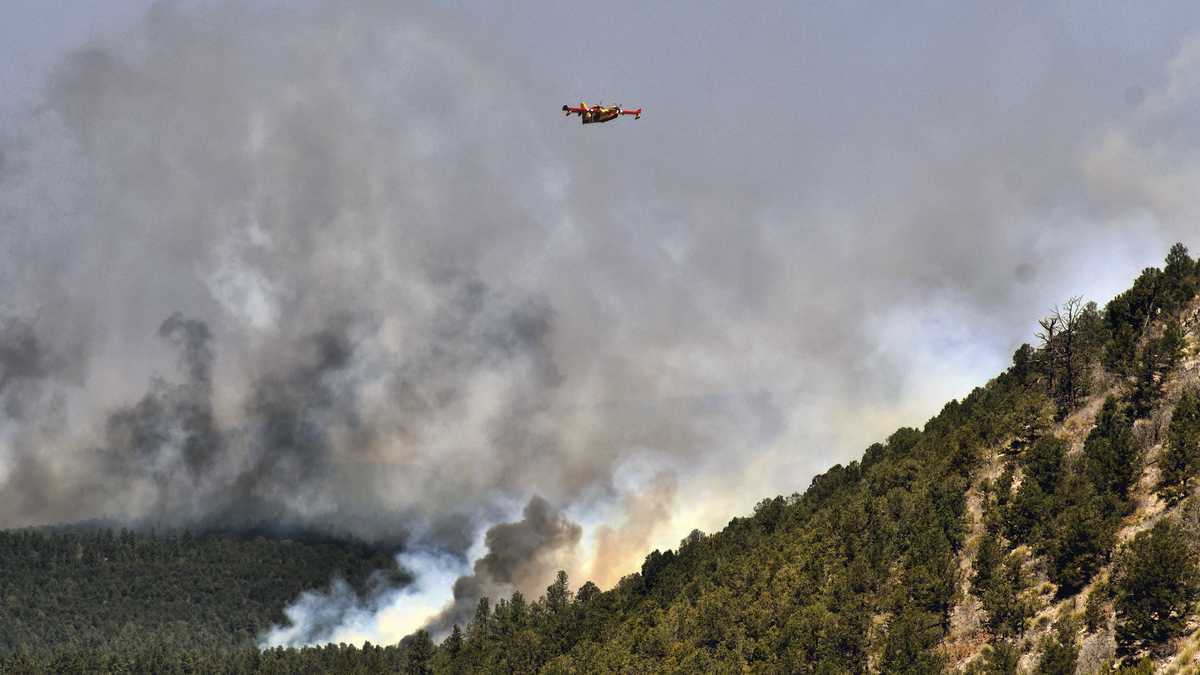 Un avión para combatir incendios vuela sobre un incendio forestal el miércoles 4 de mayo de 2022, cerca de la ciudad de Las Vegas, Nuevo México. (AP Foto/Thomas Peipert)