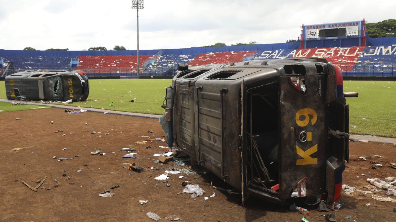 Police cars lie on their side wrecked on the pitch at Kanjuruhan Stadium in Malang, East Java, Indonesia, Sunday, Oct. 2, 2022. Panic at an Indonesian soccer match Saturday left over 100 people dead, most of whom were trampled to death after police fired tear gas to prevent violence. (AP/Trisnadi)
