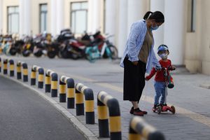 Una mujer y un niño con máscaras para protegerse del coronavirus caminan por una calle en Beijing el lunes 17 de mayo de 2021 (AP Photo / Ng Han Guan).
