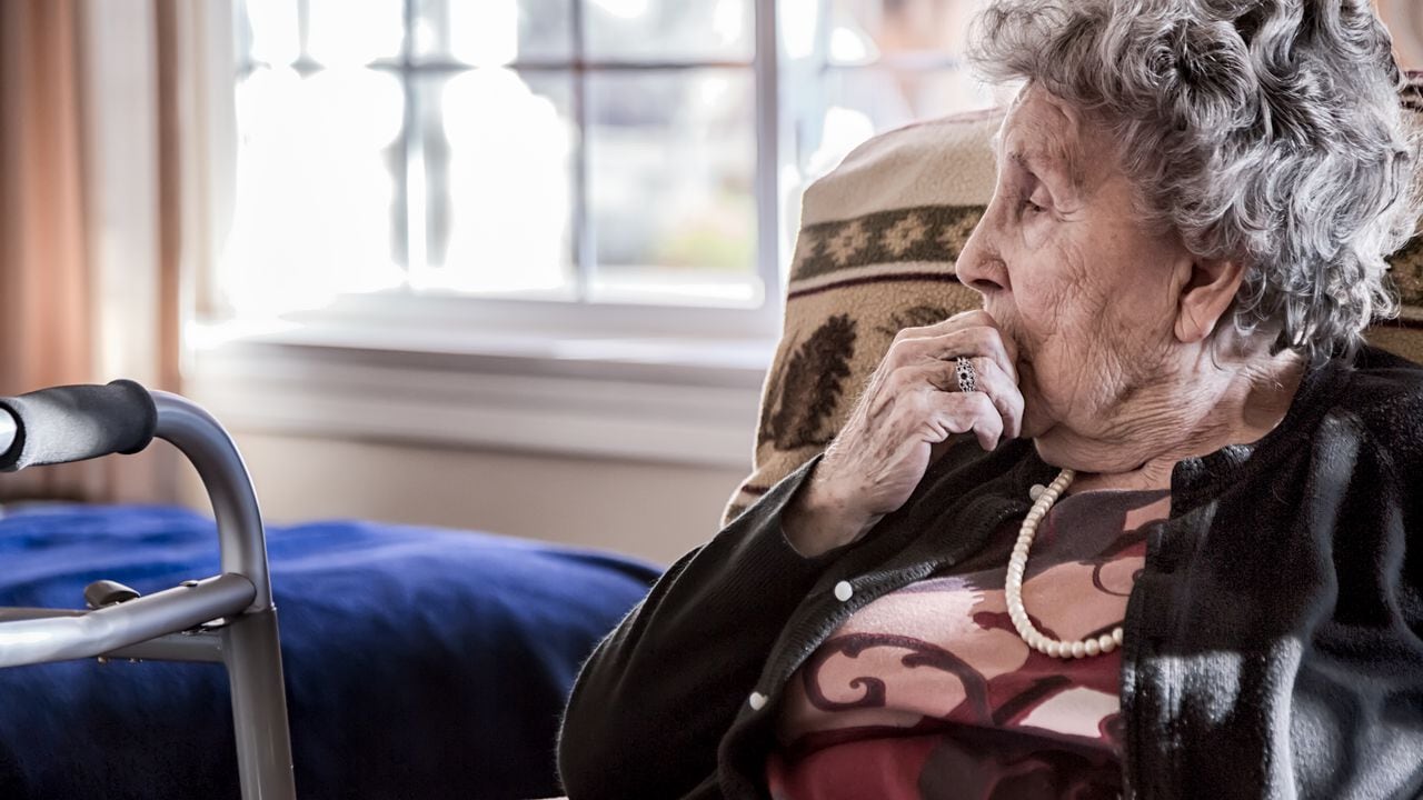 Retrato de una anciana sentada sola en un centro de atención para personas mayores
