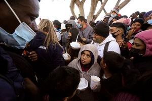 FILE - In this Friday, Feb. 19, 2021, file photo, asylum seekers receive food as they wait for news of policy changes at the border, in Tijuana, Mexico. The Biden administration hopes to relieve the strain of thousands of unaccompanied children coming to the southern border by terminating a 2018 Trump-era order that discouraged potential family sponsors from coming forward to house the children. (AP Photo/Gregory Bull, File)