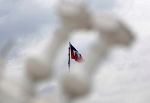 FILE PHOTO: The Haitian flag, photographed through two of the balusters remaining on a balcony of the collapsed National Palace, flies from a pole on the front lawn in Port-au-Prince August 13, 2012. Picture taken August 13, 2012. REUTERS/Swoan Parker/File Photo
