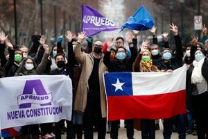 People wave as they hold flags of approval of the new Constitution and a Chilean flag on July 6, 2022 in Santiago. - The campaign for the September 4 plebiscite to approve or reject the text of a new Constitution began Wednesday in Chile. (Photo by JAVIER TORRES / AFP)