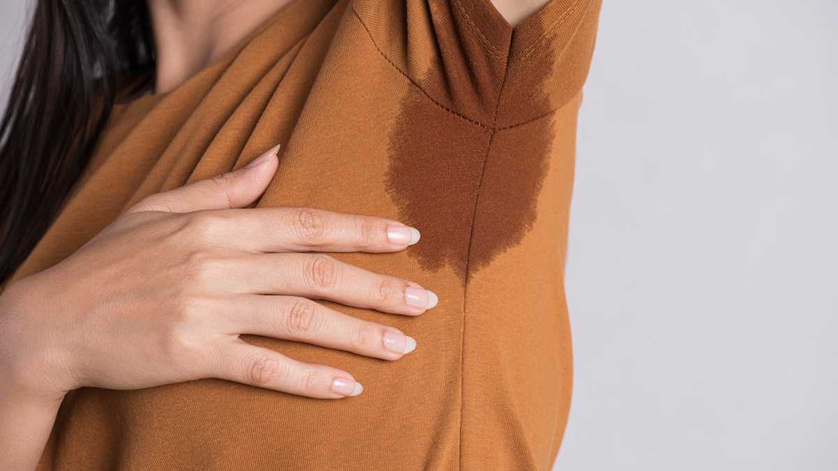 Close-up asian woman with hyperhidrosis sweating. Young asia woman with sweat stain on her clothes against grey background. Healthcare concept.