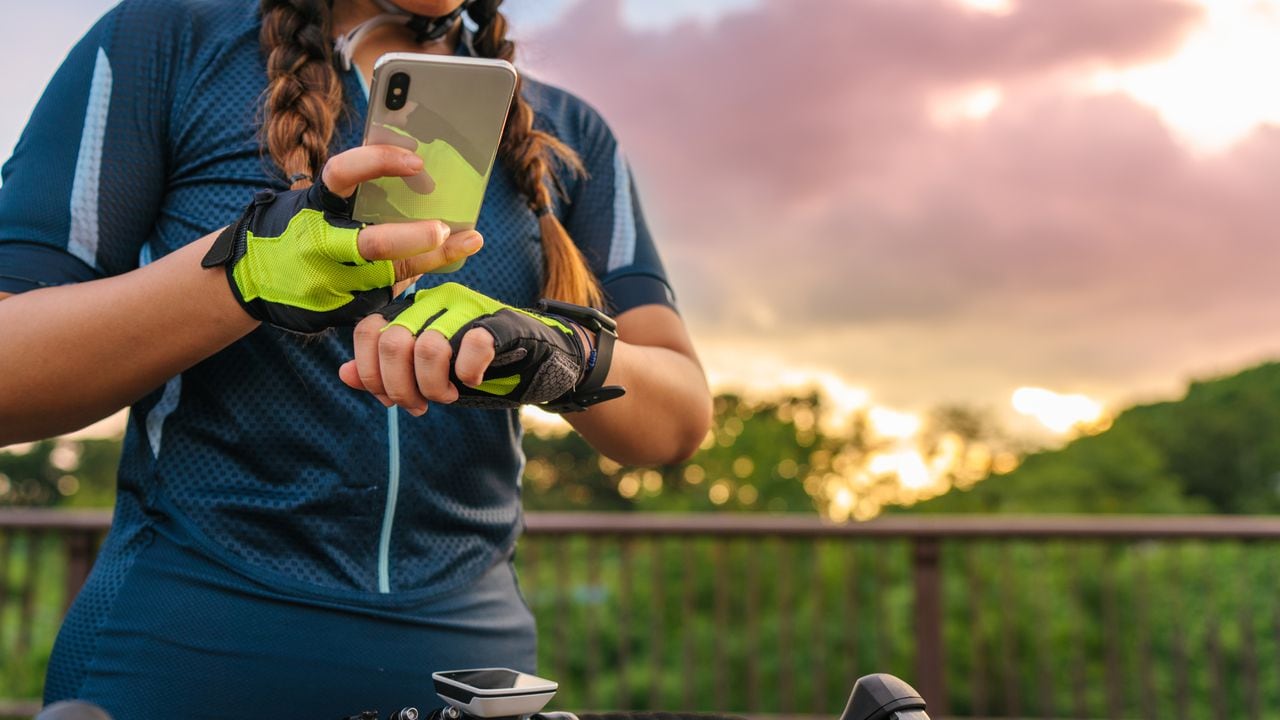 Una ciclista está configurando su reloj inteligente y su teléfono inteligente antes de andar en bicicleta.