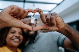Couple second key to new home with hand in heart symbol