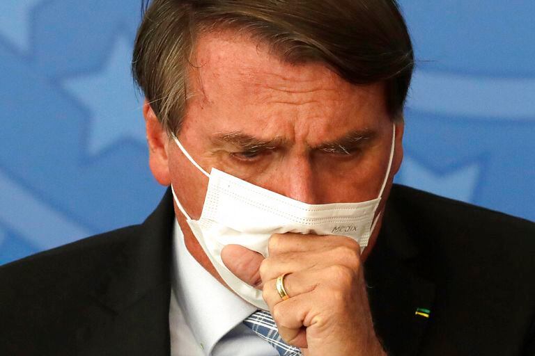 Brazilian President Jair Bolsonaro coughs through his mask during a ceremony to sign a law that expands the federal government's ability to acquire COVID-19 vaccines, at Planalto presidential palace in Brasilia, Brazil, Wednesday, March 10, 2021. (AP Photo/Eraldo Peres)