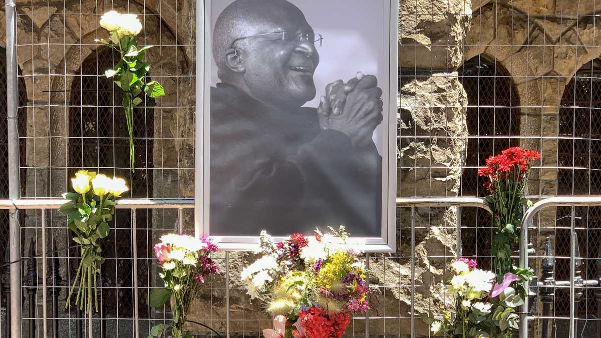 Flores junto a un retrato del ícono sudafricano anti-apartheid Desmond Tutu afuera de la catedral de San Jorge en Ciudad del Cabo el 26 de diciembre de 2021, luego de la noticia del fallecimiento de Tutu. - El ícono sudafricano anti-apartheid Desmond Tutu, descrito como la brújula moral del país, murió el 26 de diciembre de 2021, a los 90 años.(Photo by Gianluigi GUERCIA / AFP)
