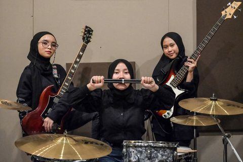 En esta foto tomada el 8 de abril de 2021, los miembros de la banda indonesia de heavy metal Voice of Baceprot (VOB), la guitarrista y vocalista Firda Marsya Kurnia (izq.), la baterista Euis Siti Aisah (c) y la bajista Widi Rahmawati (der.) posan para las fotos después de una sesión de práctica en Yakarta. Foto de Bay Ismoyo / AFP)