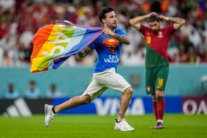 Un invasor de la cancha corre por el campo con una bandera del arcoíris durante el partido de fútbol del grupo H de la Copa Mundial entre Portugal y Uruguay, en el Estadio Lusail en Lusail, Qatar, el lunes 28 de noviembre de 2022.