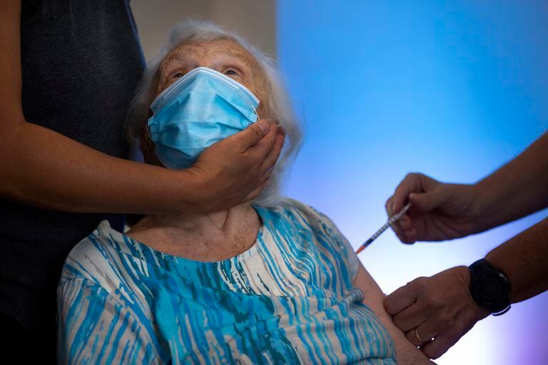 Blossom Koppelman, de 86 años, recibe una tercera vacuna Pfizer-BioNTech COVID-19 de un voluntario del servicio de emergencia nacional Magen David Adom, en un hogar de ancianos privado, en Netanya, Israel, el domingo 1 de agosto de 2021. Las autoridades de salud israelíes comenzaron a administrar el coronavirus vacunas de refuerzo el viernes a personas mayores de 60 años que ya han recibido ambas dosis de una vacuna, en un intento por combatir un aumento reciente en los casos. (Foto AP / Oded Balilty)