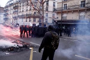 Un manifestante se para frente a la policía antidisturbios francesa mientras los fuegos artificiales estallan en medio de enfrentamientos durante una manifestación como parte del décimo día de huelgas y protestas nacionales contra la reforma de pensiones del gobierno francés, en París, Francia, el 28 de marzo de 2023.