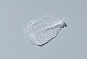 Transparent cosmetic cream on gray background. Vaseline; hard cream. . Drop of liquid foundation strokes.