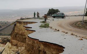 People stand in a damaged road as a powerful storm and heavy rainfall flooded hit Shahhat city, Libya, September 11, 2023. REUTERS/Omar Jarhman NO RESALES. NO ARCHIVES. REFILE - REMOVING WATERMARK