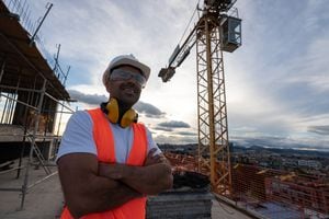 Retrato de un trabajador reflexivo en un sitio de construcción con un casco y equipo de protección y sonriendo