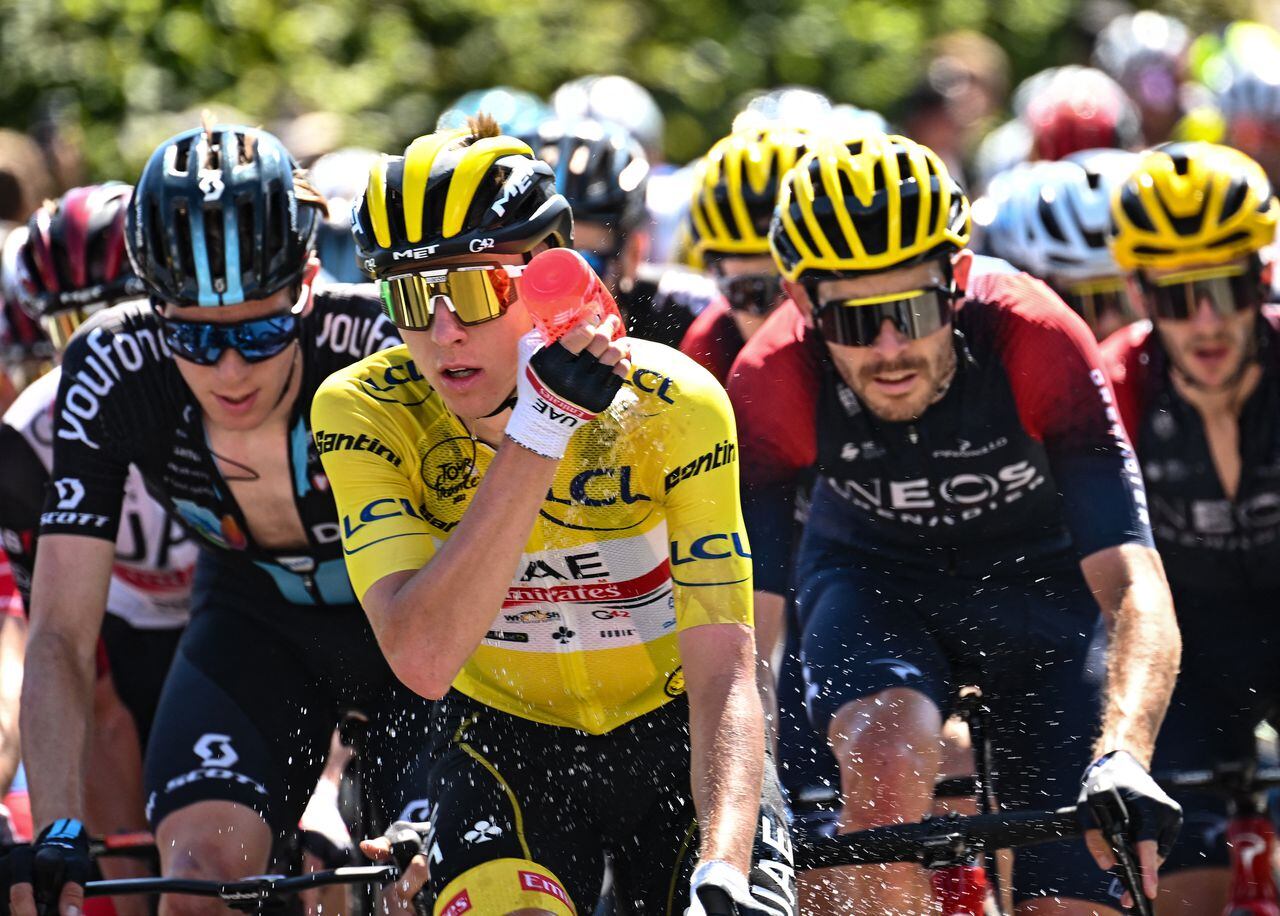 UAE Team Emirates team's Slovenian rider Tadej Pogacar wearing the overall leader's yellow jersey cools down with water as he cycles with the pack of riders during the 10th stage of the 109th edition of the Tour de France cycling race, 148,1 km between Morzine and Megeve, in the French Alps, on July 12, 2022. (Photo by Marco BERTORELLO / AFP)