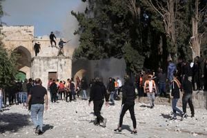 Los palestinos trabajan para extinguir un árbol que se incendió cuando la policía israelí se enfrentó a los manifestantes en el complejo de la mezquita de Al Aqsa, en la Ciudad Vieja de Jerusalén, el viernes 22 de abril de 2022.