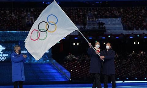 El alcalde de Milán Giuseppe Sala y el Cortina Gianpietro Ghedina (derecha) ondean la bandera olímpica frente al presidente del COI Thomas Bach durante la ceremonia de clasura de los Juegos Olímpicos de Invierno de Beijing, el domingo 20 de febrero de 2022. (AP/Jae C. Hong)