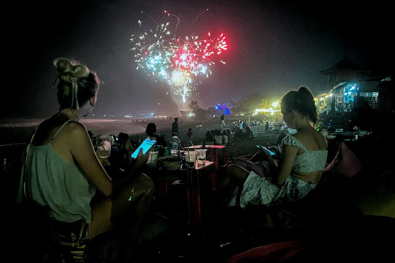 Los fuegos artificiales iluminan el cielo nocturno mientras los juerguistas celebran la víspera de Año Nuevo en la playa el 31 de diciembre de 2023 en el distrito de Kerobokan en la isla turística de Bali, Indonesia.