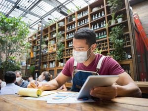 Retrato de un gerente de negocios haciendo los libros en un restaurante con una máscara facial durante la pandemia de COVID-19 - reapertura del negocio
