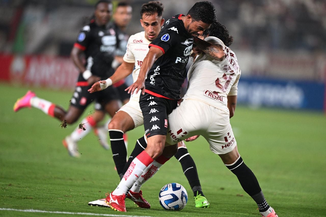 Santa Fe's midfielder Christian Marrugo (L) and Universitario's Paraguayan defender Williams Riveros vie for the ball during the Copa Sudamericana group stage first leg football match between Peru's Universitario and Colombia's Independiente Santa Fe, at the Monumental de Ate stadium in Lima, on May 4, 2023. (Photo by ERNESTO BENAVIDES / AFP)