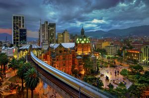 El metro elevado de Medellín está en movimiento mientras se precipita hacia la estación Parque Berrio frente al iluminado Palacio de la Cultura en la Plaza Botero en Medellín, Colombia. La Ciudad de la Eterna Primavera está ubicada en el Valle de Aburrá, una región central de la Cordillera de los Andes en América del Sur.