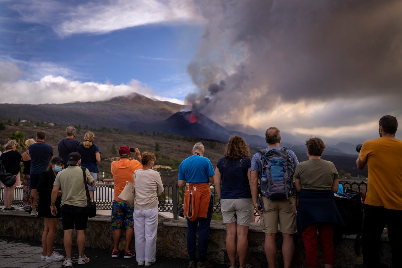 Los turistas miran y toman fotos de un volcán mientras continúa en erupción en la isla canaria de La Palma, España, el martes 26 de octubre de 2021.