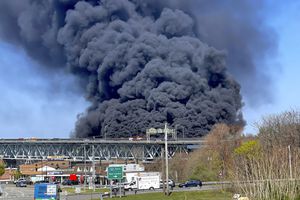 En esta foto provista por la policía estatal de Connecticut, gruesas columnas de humo se alzan de un incendio provocado por el choque entre un camión cisterna de combustibles y un auto en el puente  Gold Star Memorial en Groton,  Connecticut, viernes 21 de abril de 2023. (Connecticut State Police via AP)