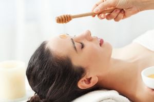 Mujer que tiene masaje facial de miel en el salón de spa
