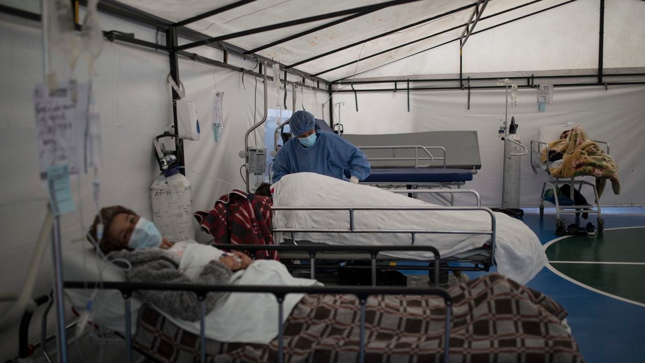 Un trabajador de la salud atiende a un paciente con COVID-19 en una carpa instalada en la cancha de fútbol del Hospital Samaritana, en Bogotá. (Foto AP / Ivan Valencia)