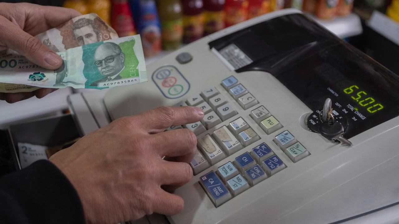 Colombian money, pesos, in hand in a cash register . concept of economics